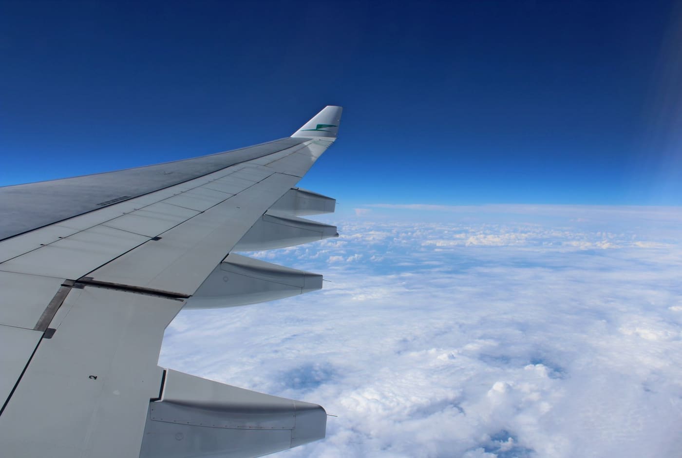 An airplane wing seen from a window above a layer of clouds