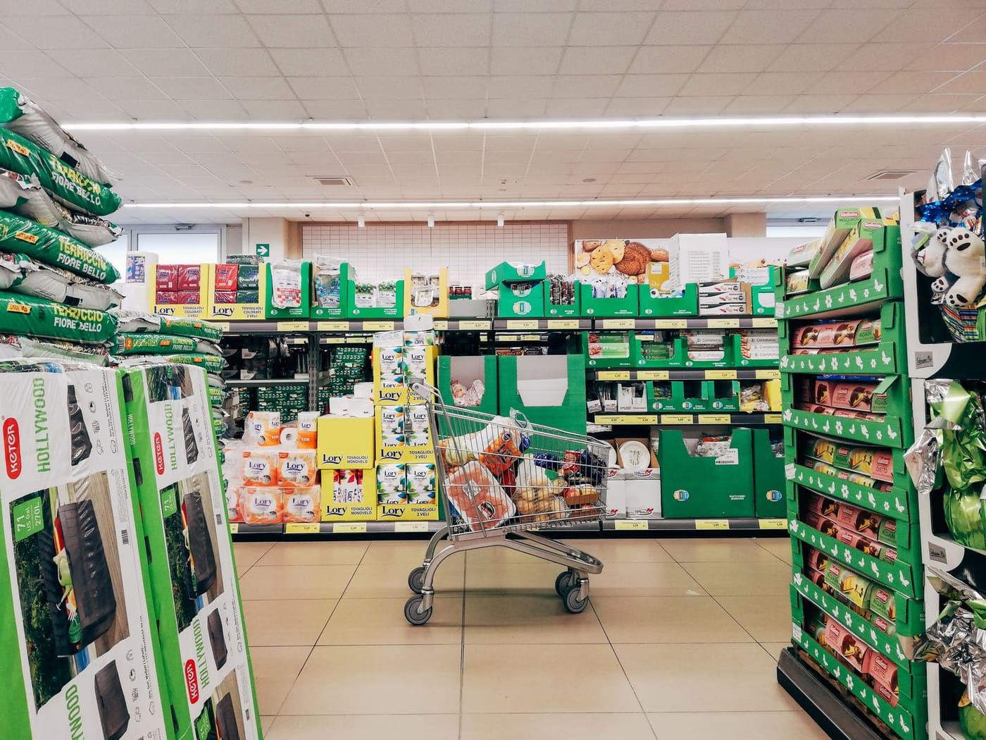 A shopping cart standing in a bright supermarket aisle
