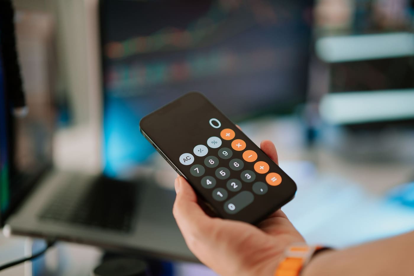 A hand holding a smartphone open to its calculator